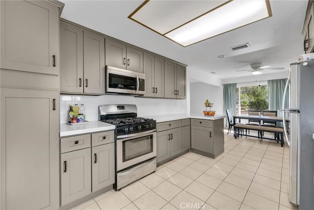 kitchen featuring stainless steel appliances, gray cabinets, light countertops, visible vents, and a peninsula