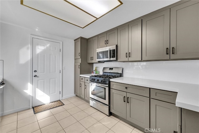 kitchen featuring tasteful backsplash, gray cabinets, stainless steel appliances, light countertops, and light tile patterned flooring