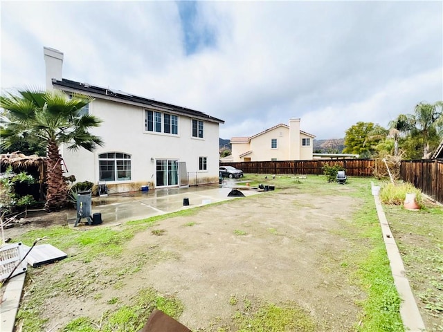 rear view of property featuring stucco siding, a lawn, a fenced backyard, and a patio area