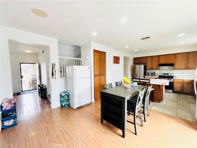 kitchen with light wood finished floors, visible vents, light countertops, brown cabinets, and appliances with stainless steel finishes