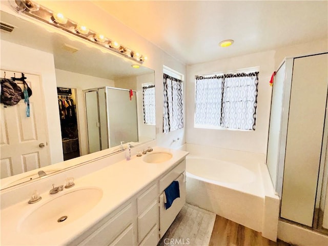 full bath with wood finished floors, double vanity, a sink, a shower stall, and a bath