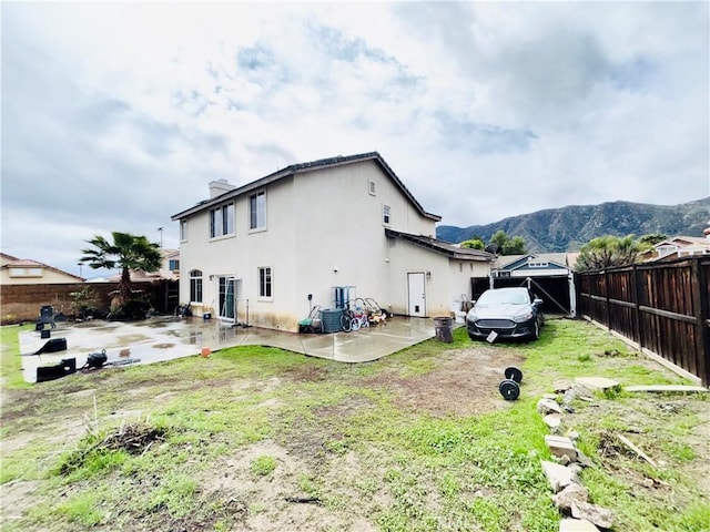 back of property featuring stucco siding, a patio, a fenced backyard, a mountain view, and a chimney