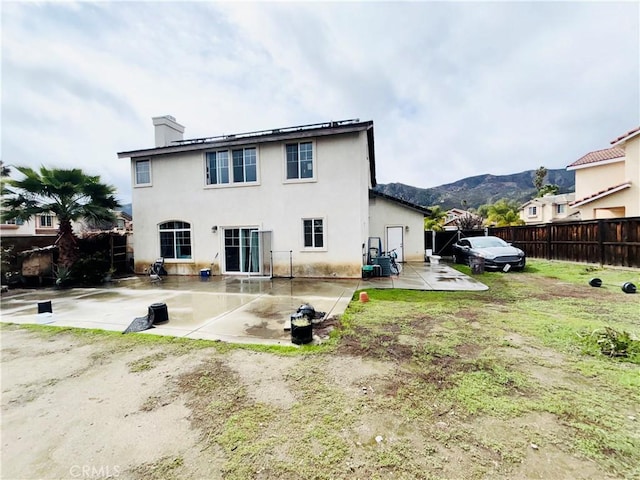 rear view of property featuring a patio, fence, a chimney, and stucco siding