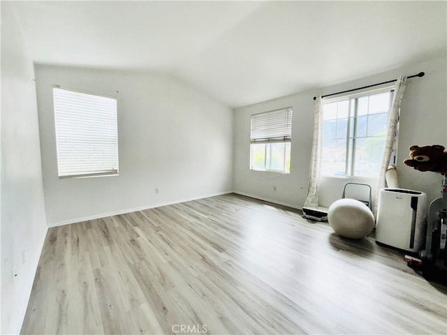 interior space featuring vaulted ceiling, wood finished floors, and baseboards