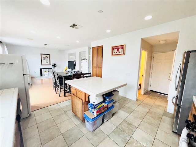 kitchen featuring light tile patterned floors, recessed lighting, visible vents, and freestanding refrigerator