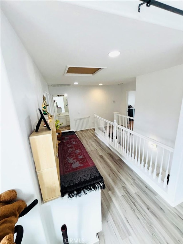 sitting room with recessed lighting, an upstairs landing, attic access, and wood finished floors