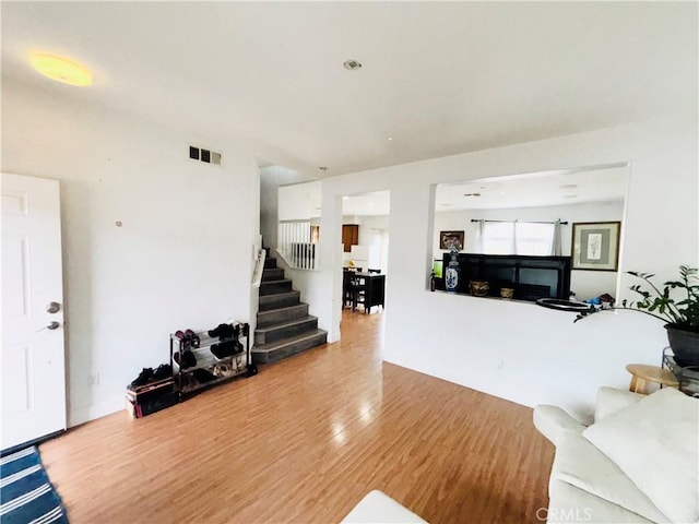 living area featuring visible vents, stairs, and wood finished floors