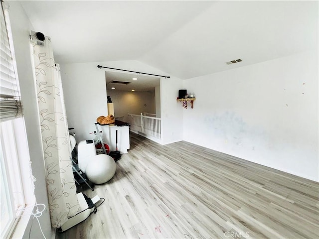 interior space with visible vents, an upstairs landing, wood finished floors, and vaulted ceiling