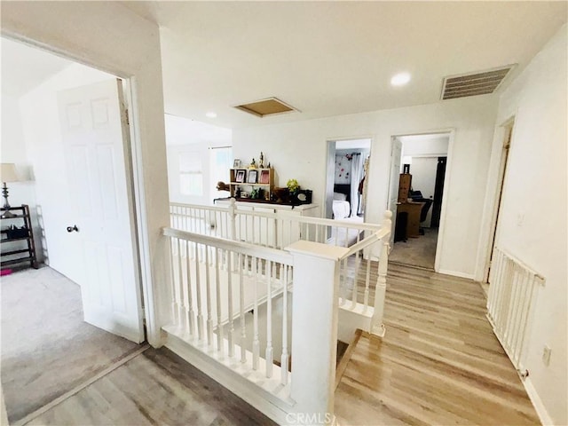 hallway with an upstairs landing, visible vents, recessed lighting, and light wood finished floors