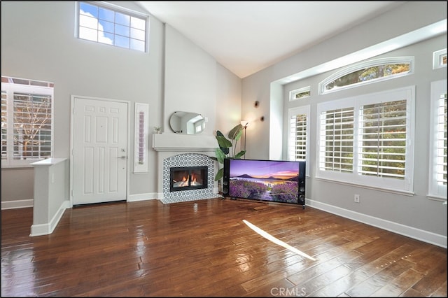 living area with hardwood / wood-style floors, a fireplace, baseboards, and high vaulted ceiling