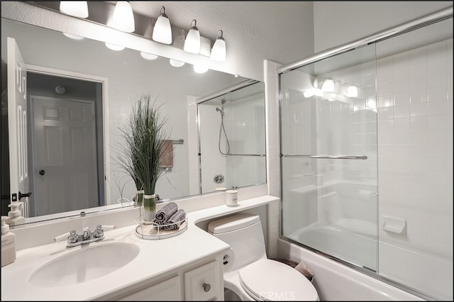 bathroom featuring enclosed tub / shower combo, toilet, vanity, and a textured wall