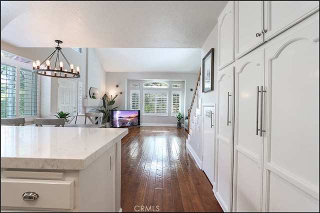 kitchen featuring a notable chandelier, a textured ceiling, dark wood-style floors, white cabinetry, and lofted ceiling