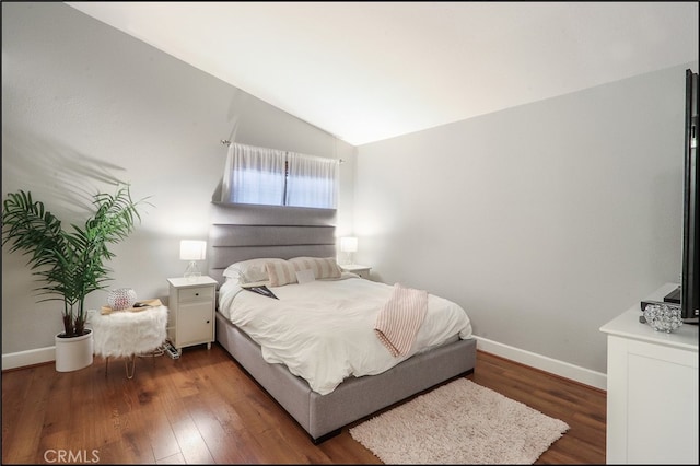 bedroom featuring wood finished floors, baseboards, and vaulted ceiling