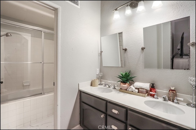 bathroom with double vanity, a textured wall, and a sink