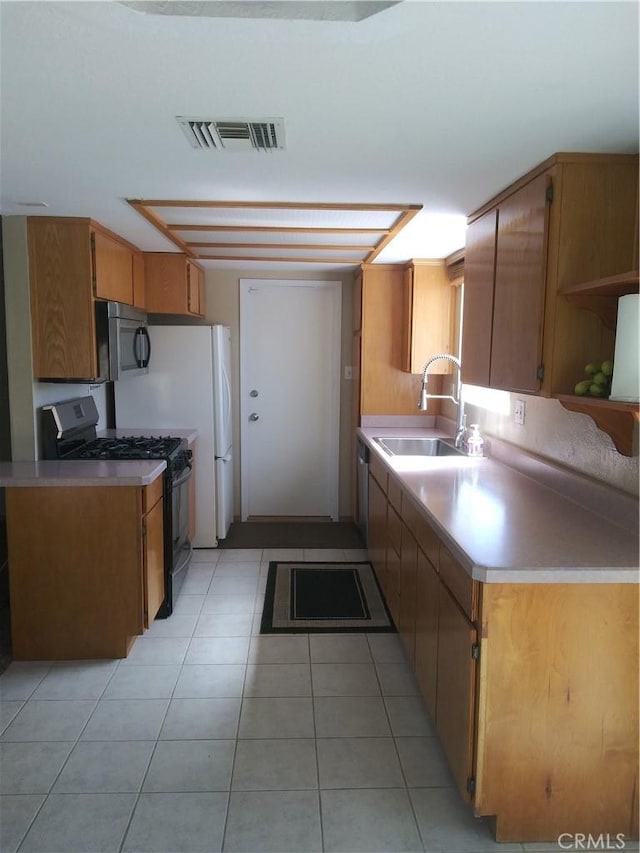 kitchen with black gas range, a sink, visible vents, light countertops, and brown cabinets