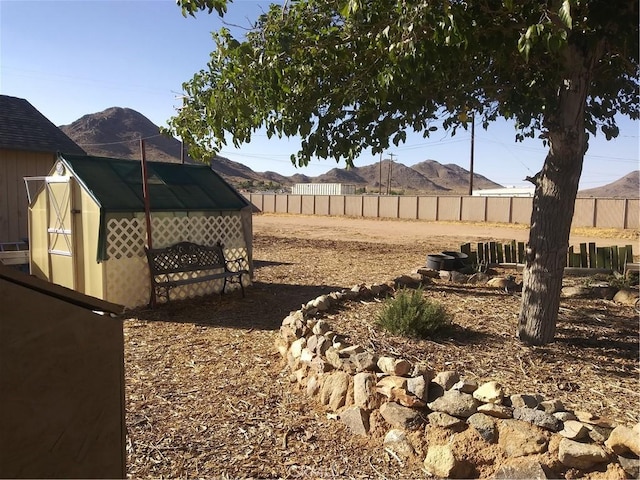 view of yard with a greenhouse, a fenced backyard, a mountain view, and an outbuilding