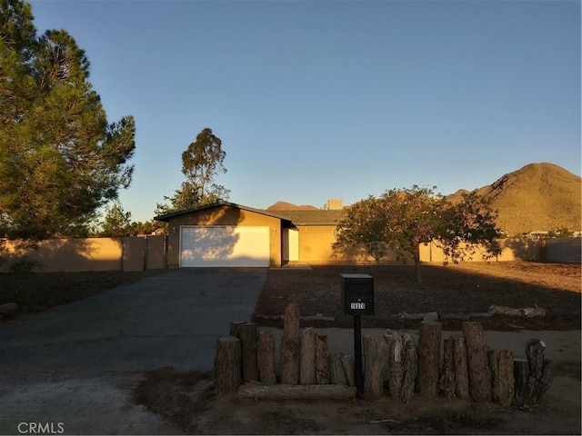 view of front of house featuring concrete driveway, an attached garage, and fence