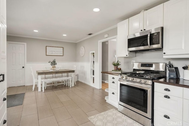 kitchen with dark countertops, recessed lighting, appliances with stainless steel finishes, white cabinets, and crown molding