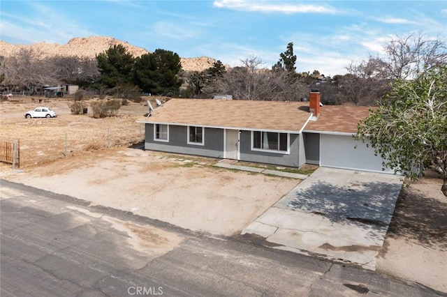 single story home featuring driveway, an attached garage, and a mountain view