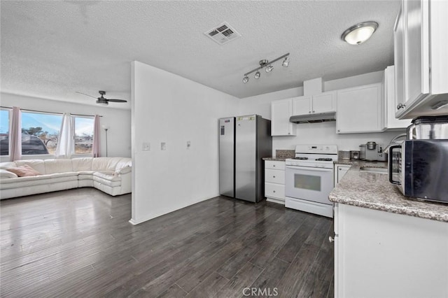 kitchen featuring under cabinet range hood, visible vents, white gas range oven, freestanding refrigerator, and dark wood finished floors