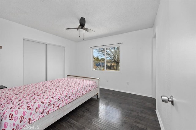 bedroom featuring a closet, dark wood-type flooring, a ceiling fan, a textured ceiling, and baseboards