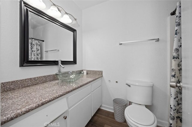 full bathroom with curtained shower, toilet, vanity, wood finished floors, and baseboards