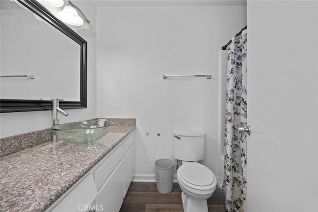 full bathroom with toilet, baseboards, wood finished floors, and vanity