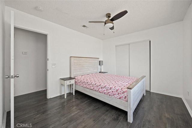 bedroom featuring a textured ceiling, dark wood-type flooring, a closet, and visible vents