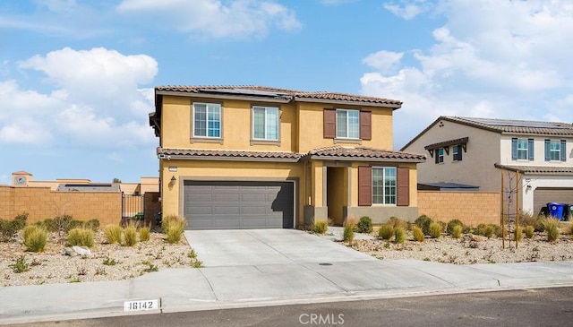 mediterranean / spanish home with solar panels, fence, concrete driveway, and stucco siding