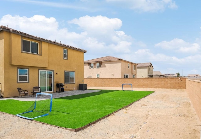 rear view of property with a yard, a patio, stucco siding, central AC unit, and a fenced backyard