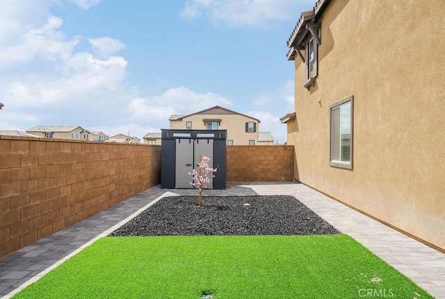 view of yard featuring a fenced backyard, a storage unit, and an outdoor structure