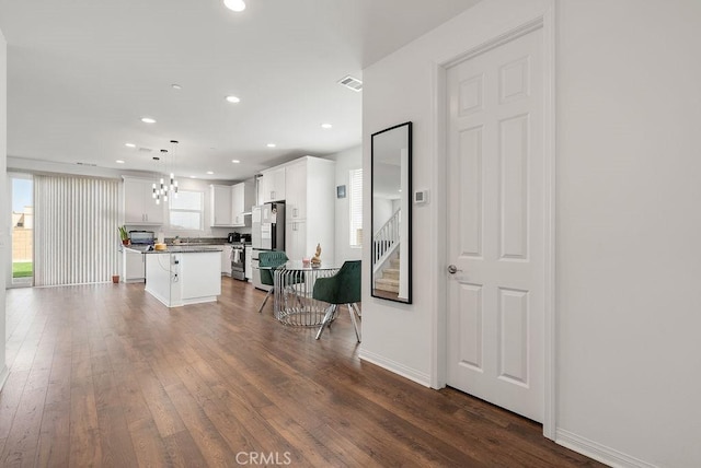 kitchen featuring dark wood-style flooring, white cabinetry, freestanding refrigerator, a center island, and dark countertops