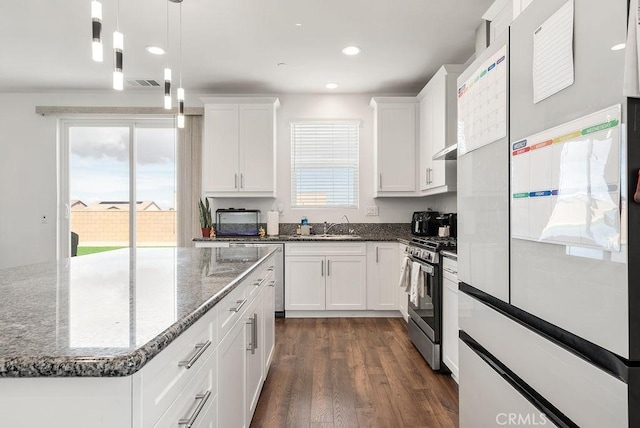 kitchen with gas stove, a sink, freestanding refrigerator, and white cabinets