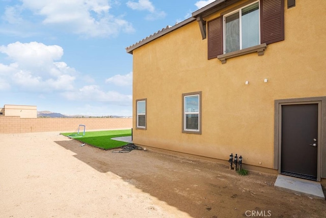 view of side of property featuring a patio area, fence, and stucco siding