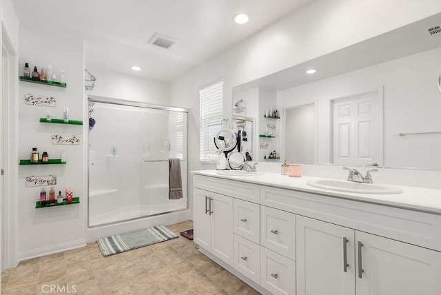 full bathroom with double vanity, a stall shower, visible vents, and a sink