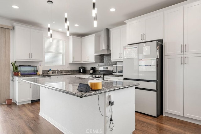 kitchen with stainless steel appliances, dark wood-style flooring, a kitchen island, and wall chimney exhaust hood