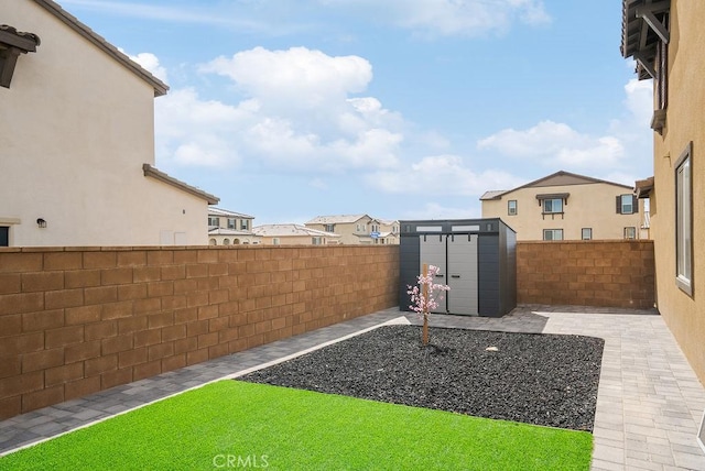 view of yard featuring an outbuilding, a storage unit, a fenced backyard, and a residential view