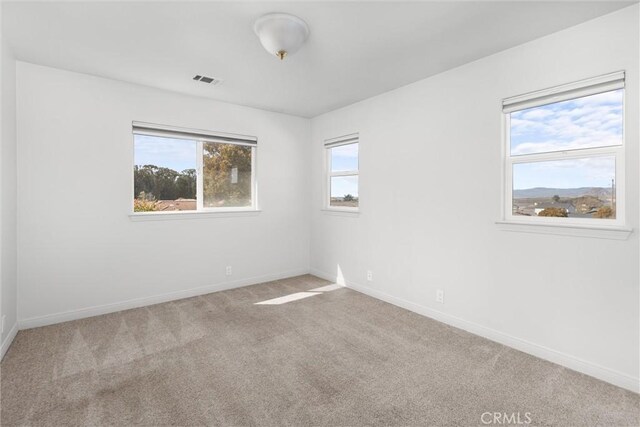 carpeted empty room featuring visible vents and baseboards