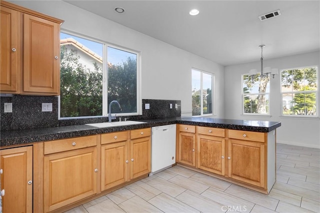 kitchen featuring visible vents, backsplash, dishwasher, a peninsula, and a sink