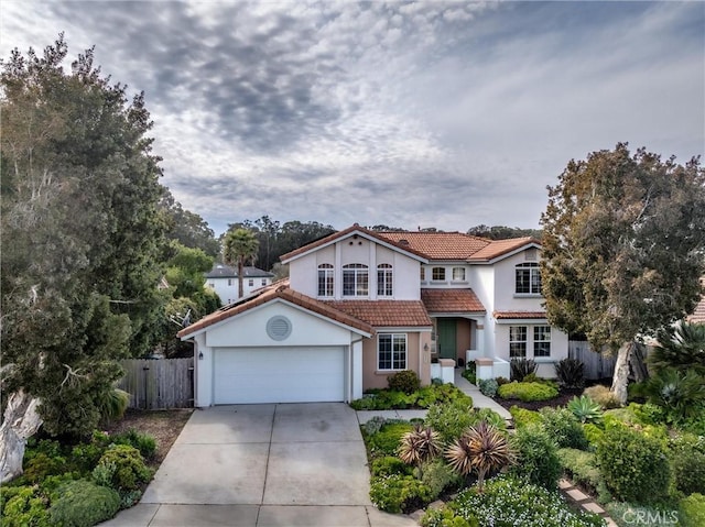 mediterranean / spanish-style home featuring stucco siding, driveway, a tile roof, fence, and an attached garage