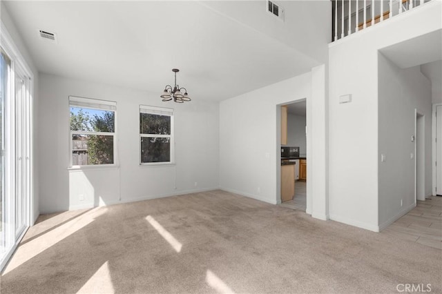 unfurnished room featuring a notable chandelier, baseboards, visible vents, and light carpet