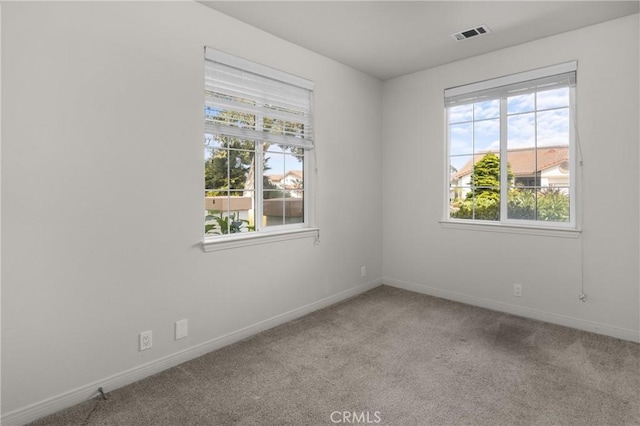 empty room featuring visible vents, carpet, and baseboards