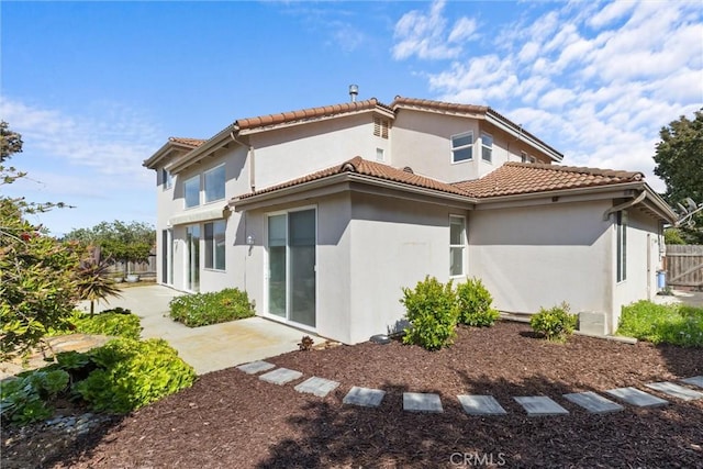 back of property with a tiled roof, stucco siding, fence, and a patio area