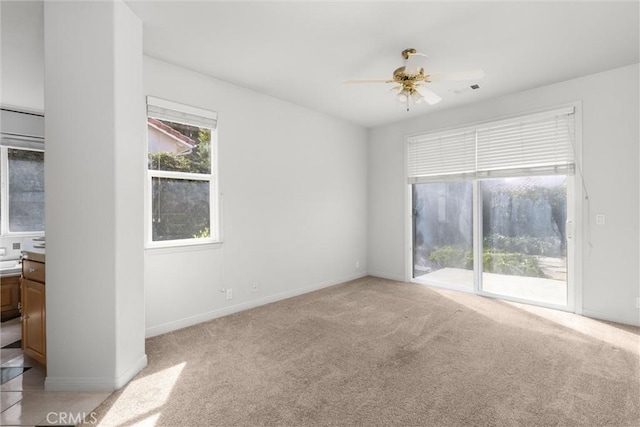 empty room with visible vents, light carpet, baseboards, and ceiling fan