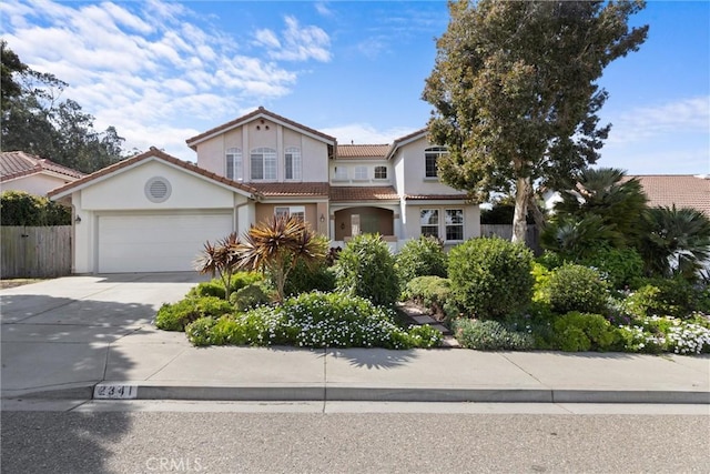 view of front of home with stucco siding, driveway, fence, a garage, and a tiled roof