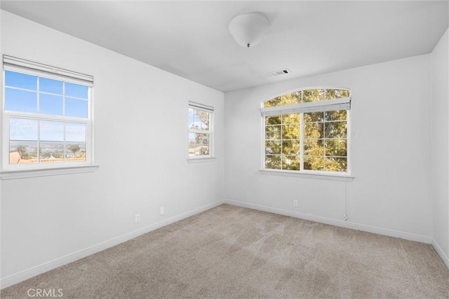 unfurnished room featuring carpet, visible vents, and baseboards