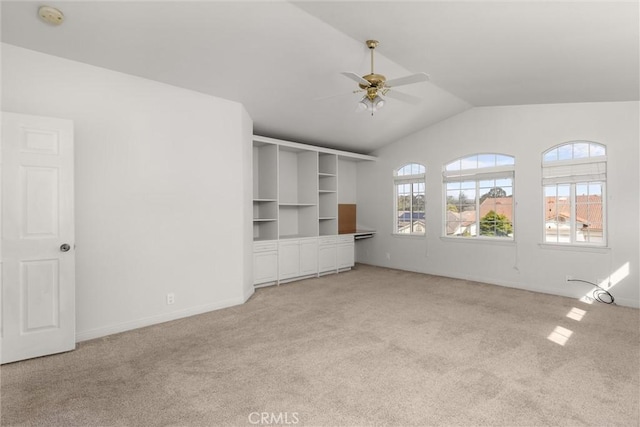 unfurnished living room featuring baseboards, lofted ceiling, light carpet, and a ceiling fan