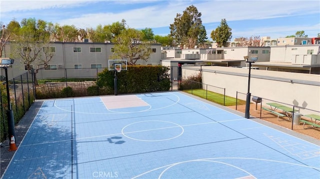 view of basketball court featuring community basketball court, fence, and a residential view