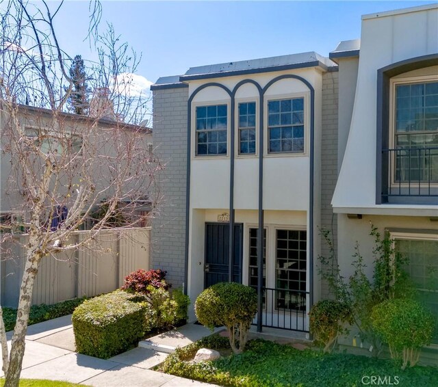 exterior space with brick siding, fence, and stucco siding