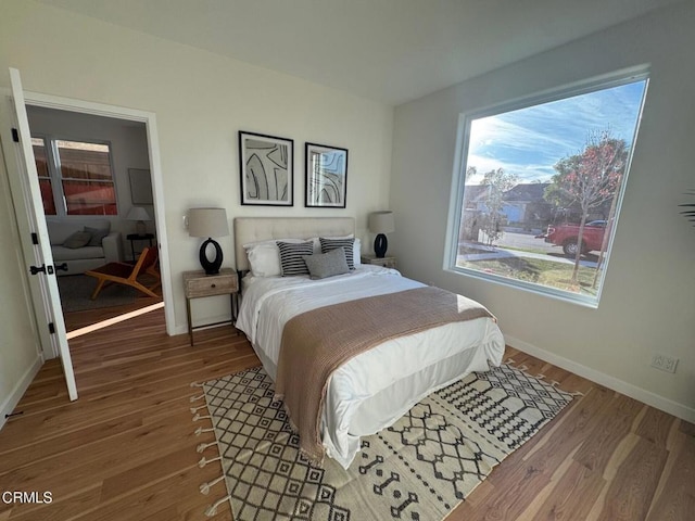 bedroom featuring multiple windows, wood finished floors, and baseboards